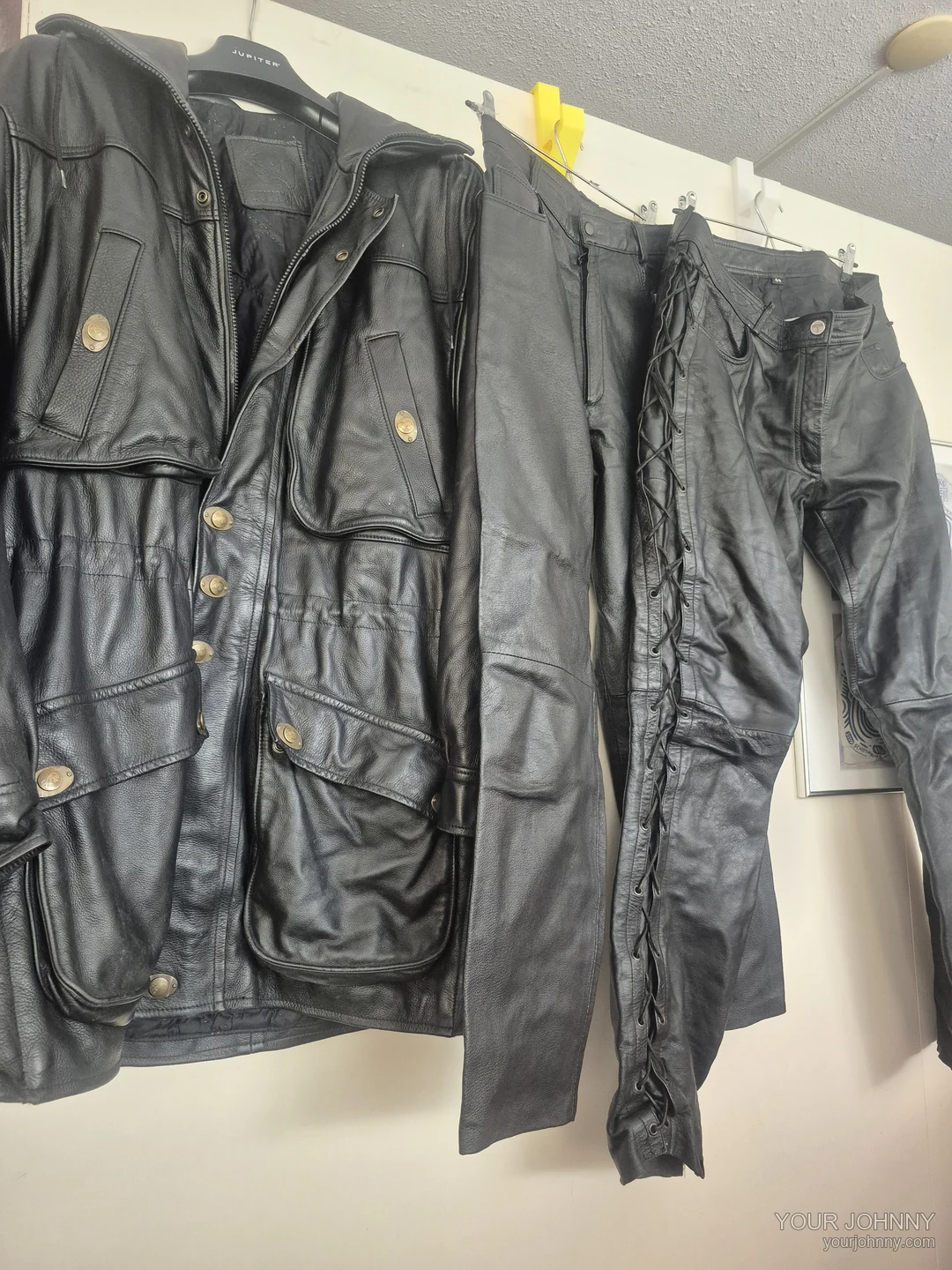 Zwarte vintage jas en twee zwarte broeken naast elkaar op hangers