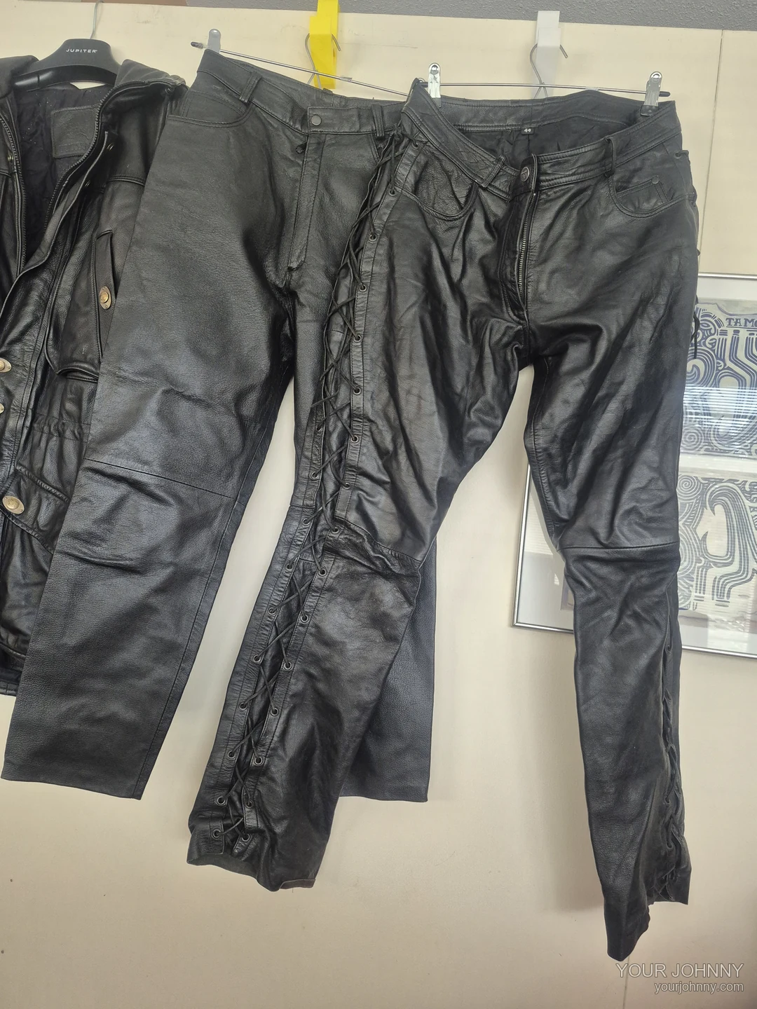 Twee zwarte vintage broeken en een deel van een zwarte jas naast elkaar op hangers
