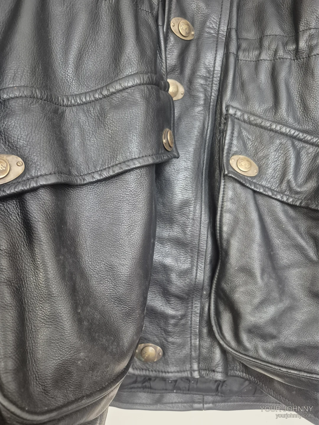 Detail van zakken, metalen knopen en stiksel van een zwarte vintage jas