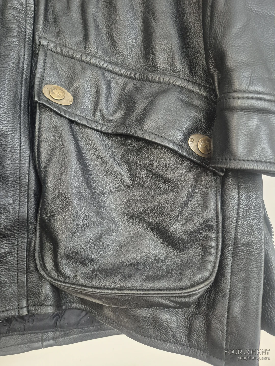 Close-up van een zak, stiksel en metalen knopen van een zwarte vintage jas