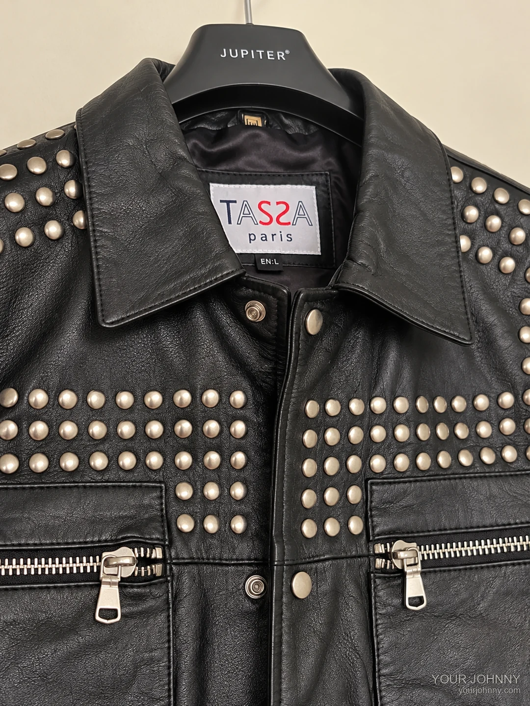 Vooraanzicht van studs, label en ritszakken van een zwarte vintage jas