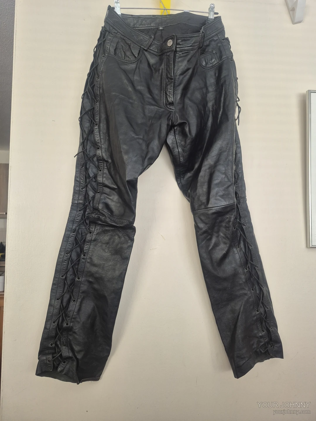 Tweede aanzicht van een zwarte vintage broek met veterdetails op een hanger