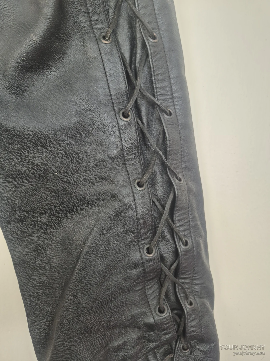 Close-up van de zijveters en leerstructuur van een zwarte vintage broek
