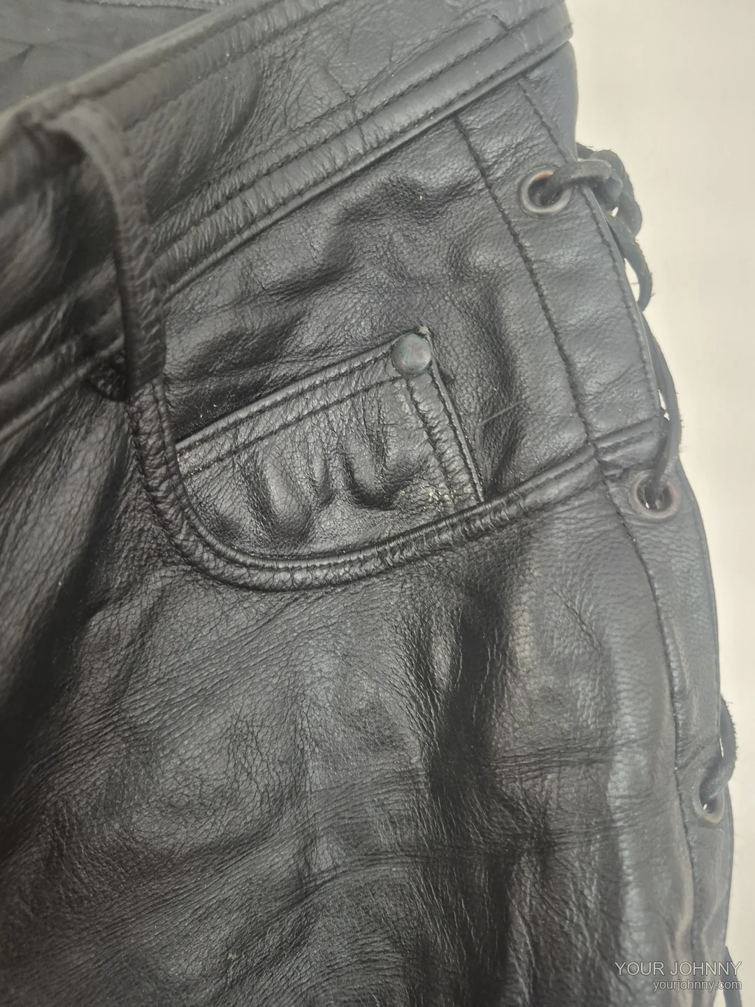 Detail van een zak, klinknagel en zijveters van een zwarte vintage broek