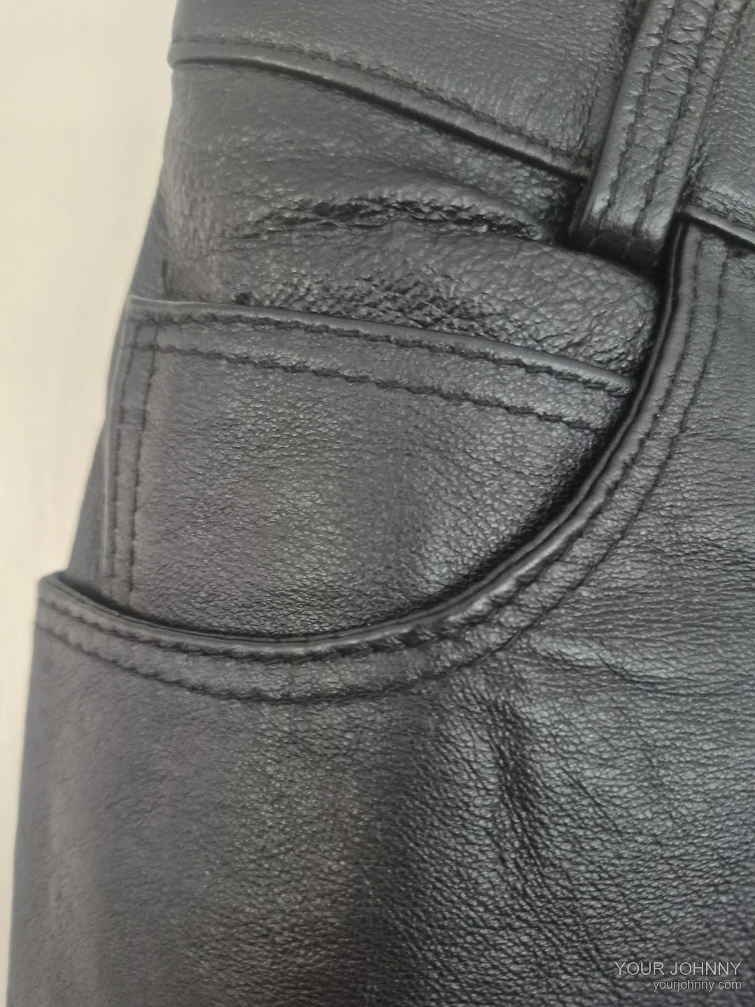 Close-up van een zak, riemlus en stiksel van een zwarte vintage broek