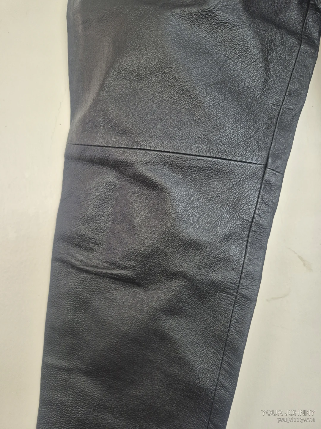 Close-up van de knie- en zijnaad van een zwarte vintage broek