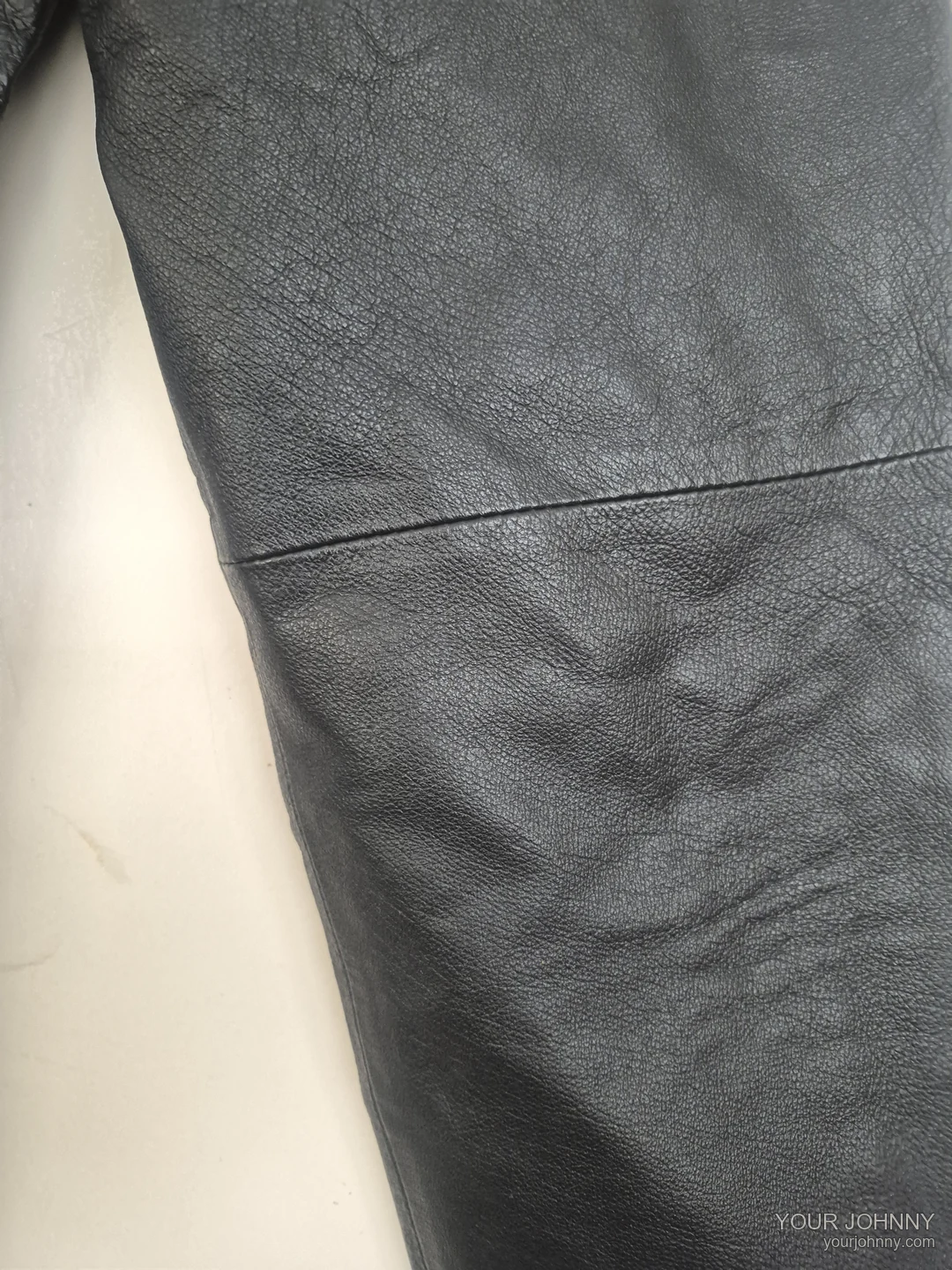 Close-up van de leerstructuur en een naad van een zwarte vintage broek