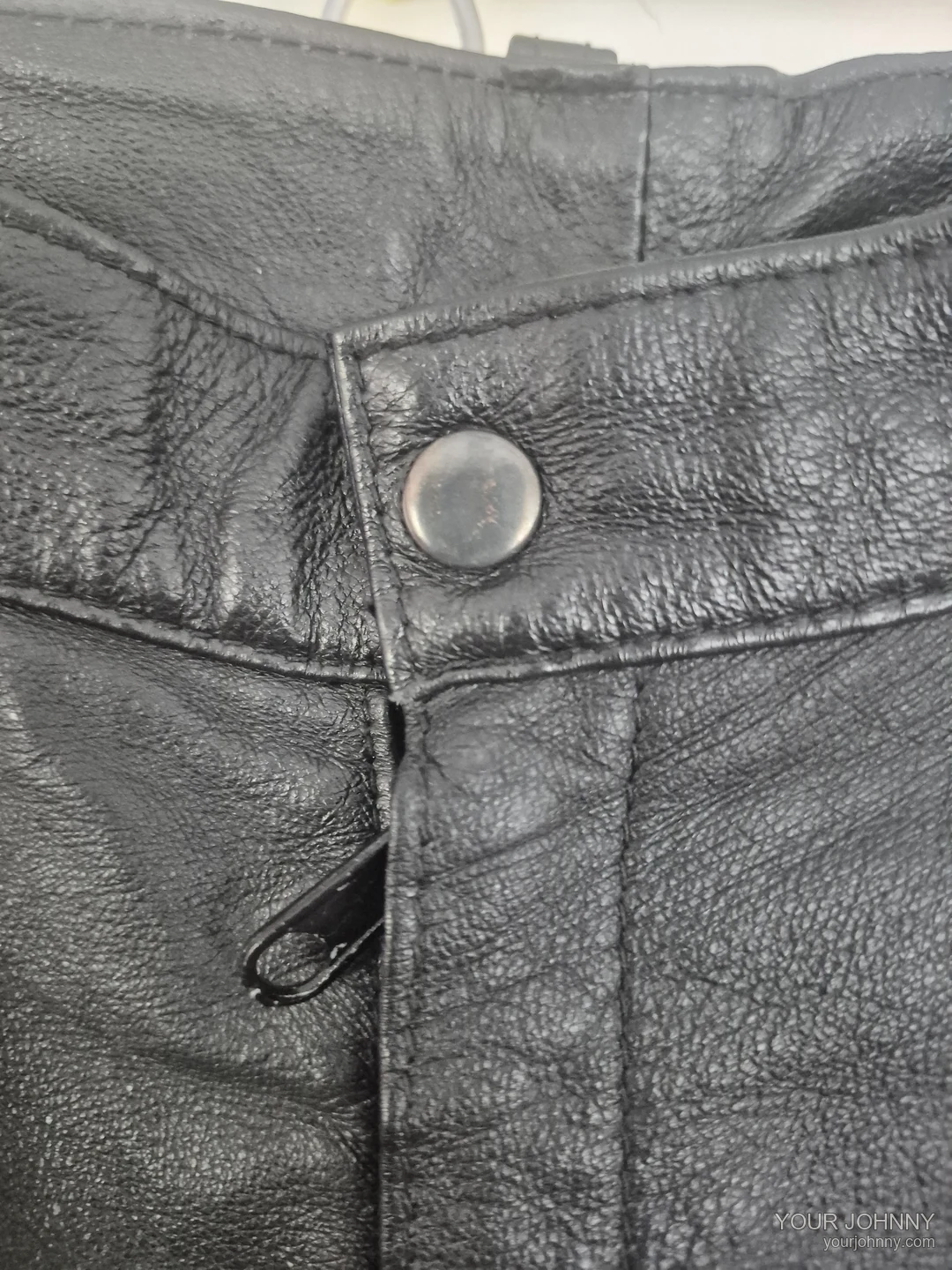 Close-up van de tailleband, knoop en ritssluiting van een zwarte vintage broek